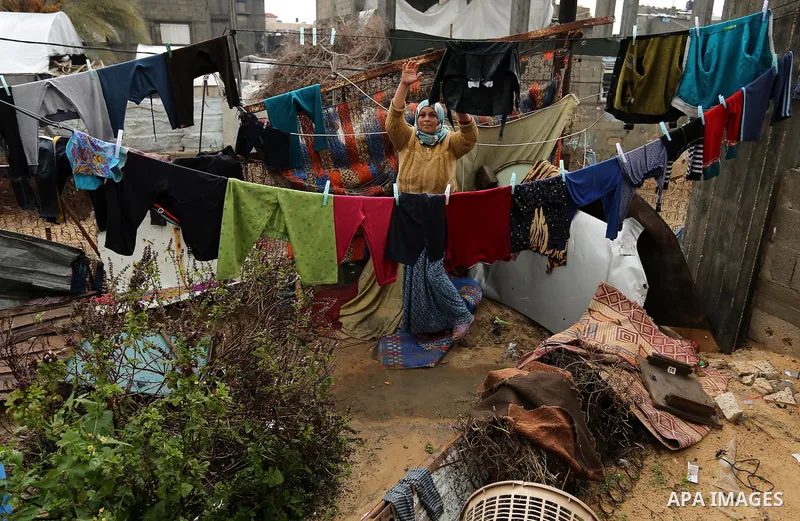 A Palestinian woman hangs laundry on a rope to dry outside her hovel in a flooded area following heavy rainfall, in the al-Moghraqa in the center Gaza Strip, on February 16, 2017. Photo by Ashraf Amra
