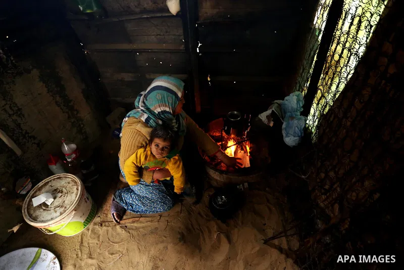 A Palestinian woman cooks food on a rainy day in Gaza city,on February 16, 2017. Photo by Ashraf Amra