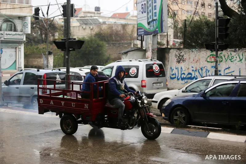 A Palestinian man rides a motorcycle during a heavy rainfall, in Gaza city, on February 16, 2017. Photo by Ashraf Amra