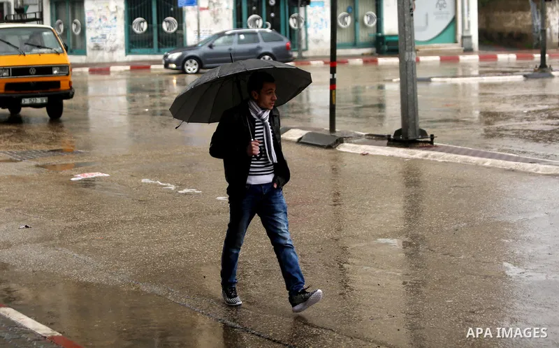 A Palestinian man walks during a heavy rainfall, in Gaza city, on February 16, 2017. Photo by Ashraf Amra