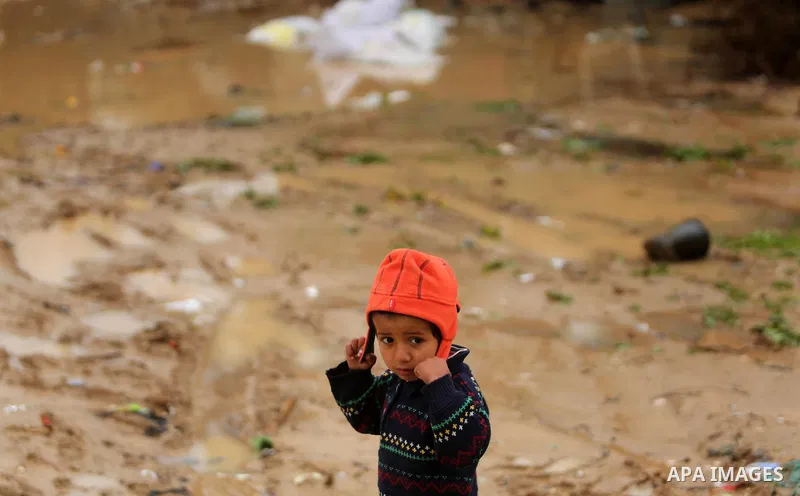 A Palestinian boy poses for a photo during a heavy rainfall, in the al-Moghraqa in the center Gaza Strip, on February 16, 2017. Photo by Ashraf Amra