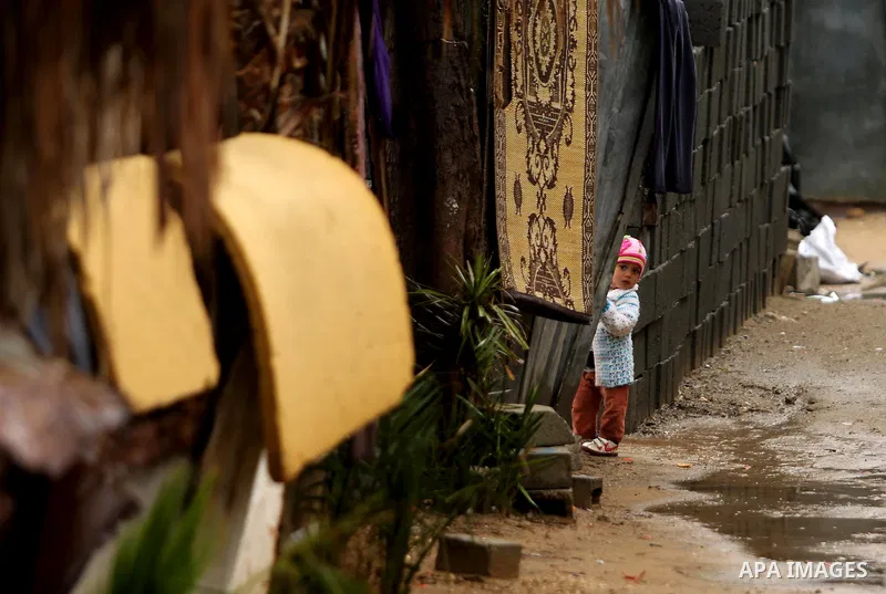 A Palestinian girl stands outside her house in a flooded area following heavy rainfall, in the al-Moghraqa in the center Gaza Strip, on February 16, 2017. Photo by Ashraf Amra