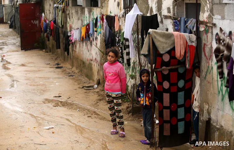 Palestinian children stand outside their house in a flooded area following heavy rainfall, in the al-Moghraqa in the center Gaza Strip, on February 16, 2017. Photo by Ashraf Amra