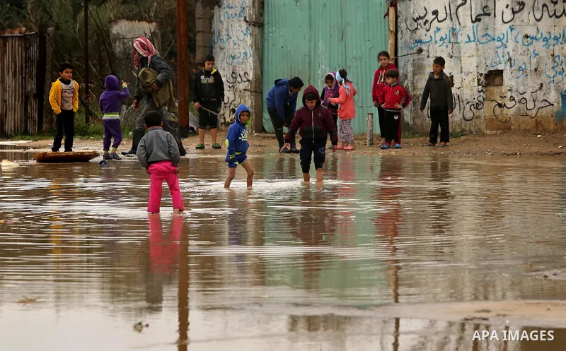 Palestinian children walk in a flooded area following heavy rainfall, in the al-Moghraqa in the center Gaza Strip, on February 16, 2017. Photo by Ashraf Amra