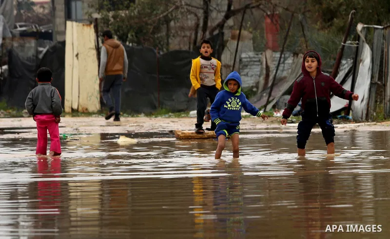 Palestinian children walk in a flooded area following heavy rainfall, in the al-Moghraqa in the center Gaza Strip, on February 16, 2017. Photo by Ashraf Amra