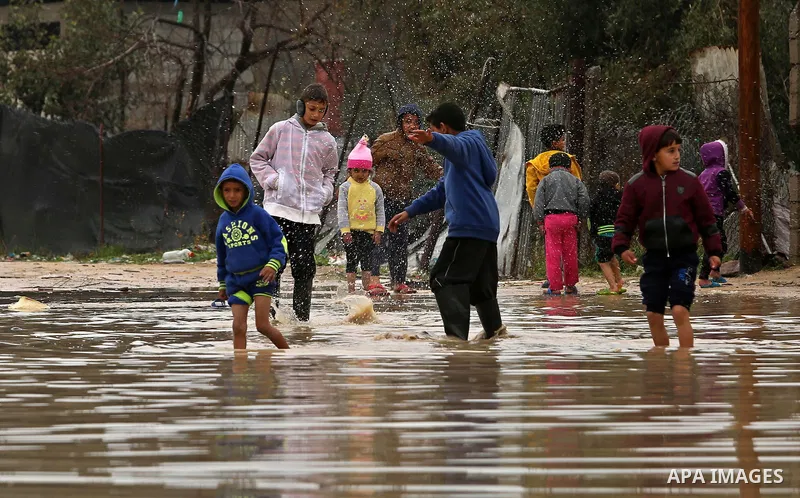 Palestinian children walk in a flooded area following heavy rainfall, in the al-Moghraqa in the center Gaza Strip, on February 16, 2017. Photo by Ashraf Amra