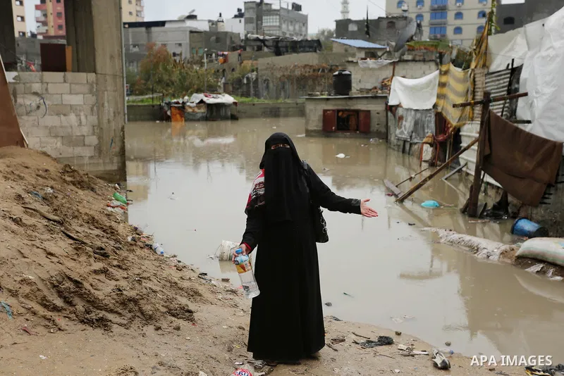 A Palestinian woman asks for help after her house was flooded following heavy rain in a neighbourhood in the northern Gaza Strip February 16, 2017. Photo by Ashraf Amra