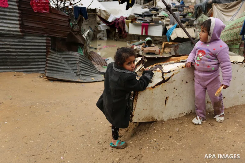 Palestinian children stand outside their family house following heavy rain in a neighbourhood in the northern Gaza Strip February 16, 2017. Photo by Ashraf Amra