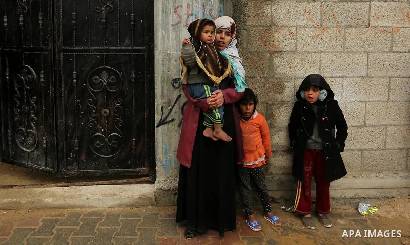 Palestinians stand outside their family house following heavy rain in a neighbourhood in the northern Gaza Strip February 16, 2017. Photo by Ashraf Amra