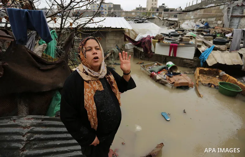 A Palestinian woman asks for help after her house was flooded following heavy rain in a neighbourhood in the northern Gaza Strip February 16, 2017. Photo by Ashraf Amra