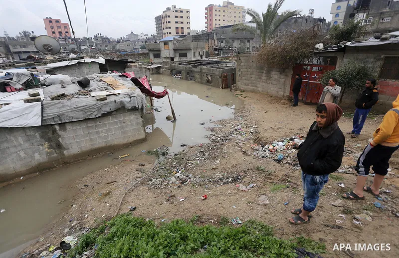 Palestinian child stand outside their family houses following heavy rain in a neighbourhood in the northern Gaza Strip February 16, 2017. Photo by Mohammed Asad