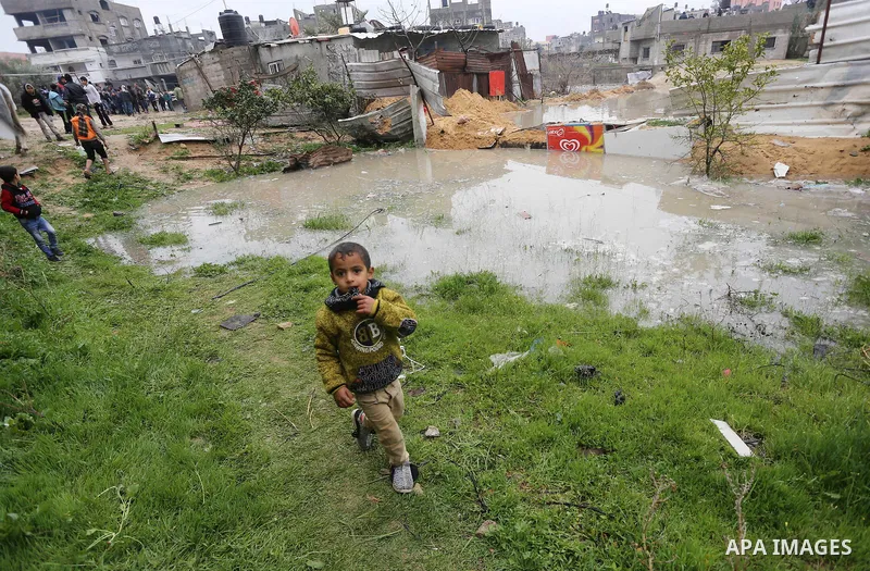 A Palestinian boy stands outside his family house following heavy rain in a neighbourhood in the northern Gaza Strip February 16, 2017. Photo by Mohammed Asad