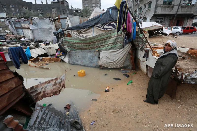 A Palestinian woman stands outside her house following heavy rain in a neighbourhood in the northern Gaza Strip February 16, 2017. Photo by Mohammed Asad