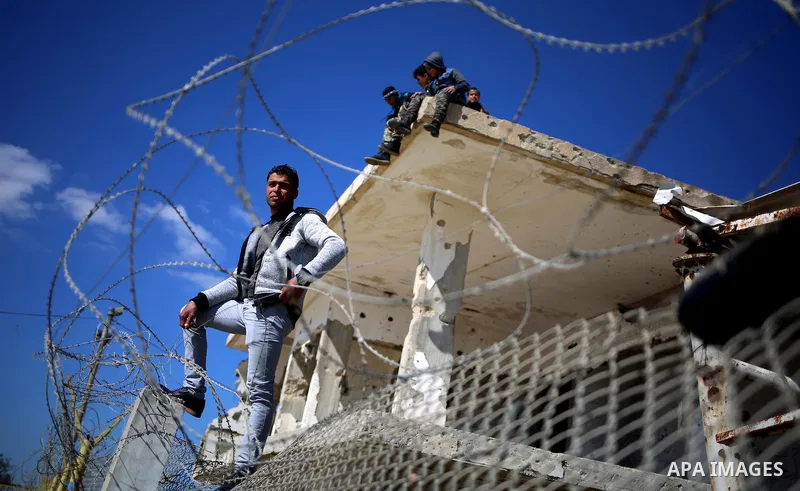 Palestinians stand behind a fence as they wait for the arrival of their relatives at Rafah crossing after it was opened by Egyptian authorities to allow stranded Palestinians to return to Gaza, in the southern Gaza Strip...