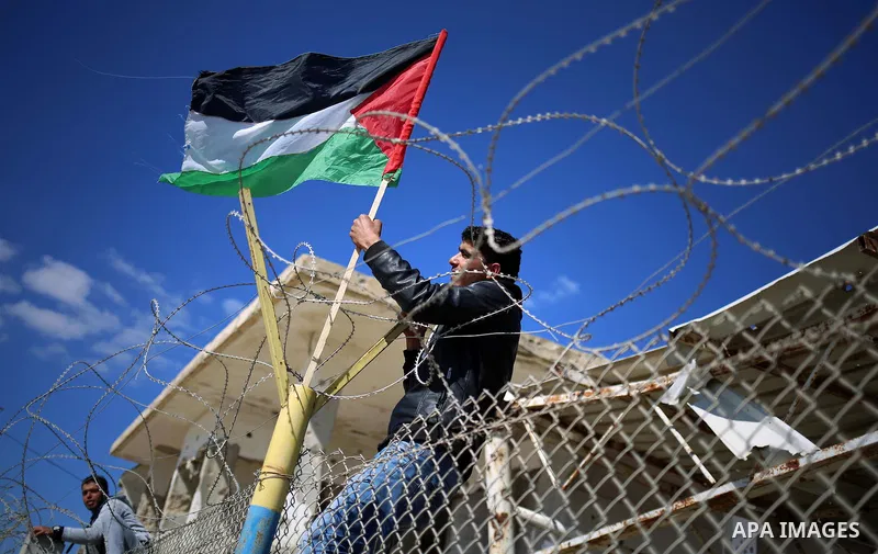 Palestinians stand behind a fence as they wait for the arrival of their relatives at Rafah crossing after it was opened by Egyptian authorities to allow stranded Palestinians to return to Gaza, in the southern Gaza Strip...