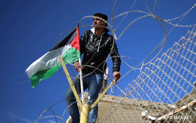 Palestinians stand behind a fence as they wait for the arrival of their relatives at Rafah crossing after it was opened by Egyptian authorities to allow stranded Palestinians to return to Gaza, in the southern Gaza Strip...