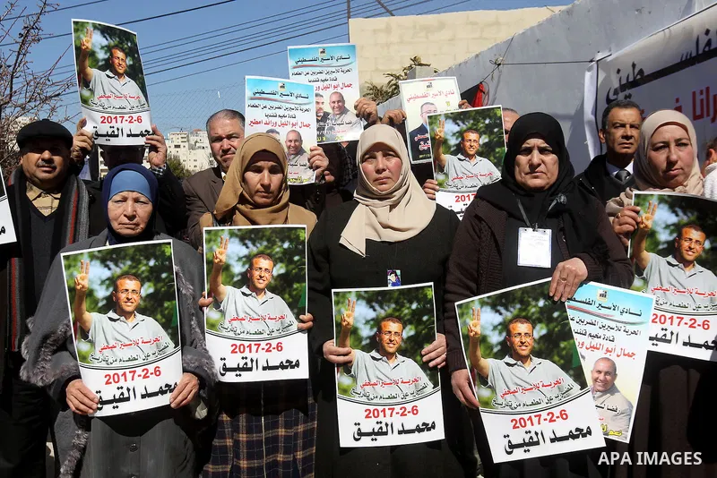 Palestinians hold placards during a protest to show solidarity with Palestinian prisoners held in Israeli Jails, in the West Bank city of Hebron, on February 20 2017. Photo by Wisam Hashlamoun
