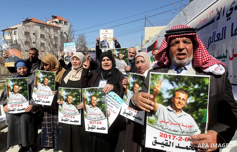 Palestinians hold placards during a protest to show solidarity with Palestinian prisoners held in Israeli Jails, in the West Bank city of Hebron, on February 20 2017. Photo by Wisam Hashlamoun