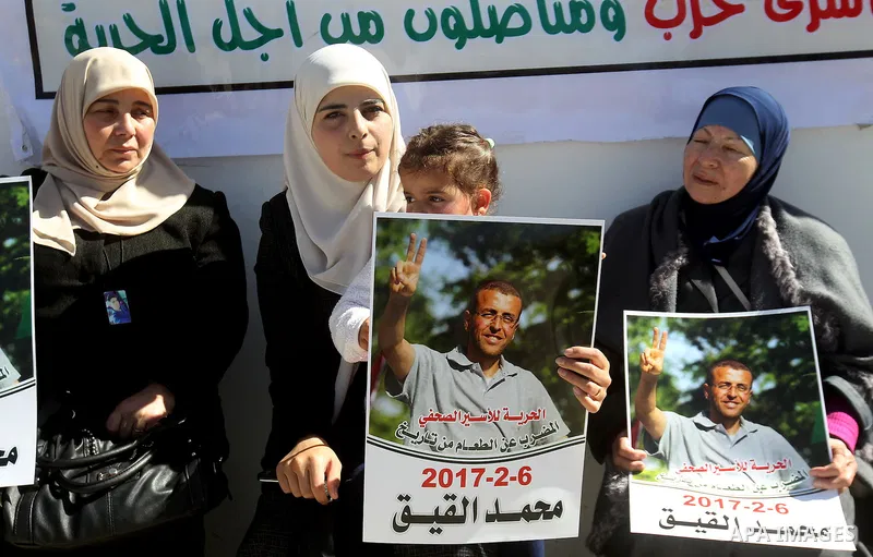 Palestinians hold placards during a protest to show solidarity with Palestinian prisoners held in Israeli Jails, in the West Bank city of Hebron, on February 20 2017. Photo by Wisam Hashlamoun