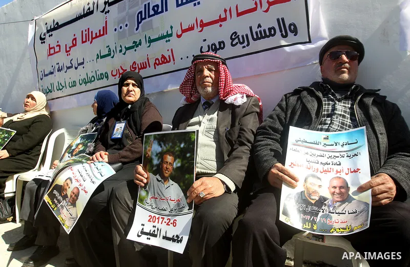 Palestinians hold placards during a protest to show solidarity with Palestinian prisoners held in Israeli Jails, in the West Bank city of Hebron, on February 20 2017. Photo by Wisam Hashlamoun