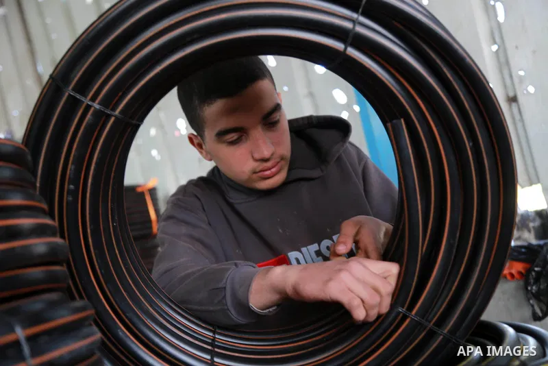 A Palestinian worker reuses plastics and metals to produce water hoses at a factory, in Gaza city, February 22, 2017. Workers collect the household recyclables, metals and plastic from landfill and garbage to sell to the...