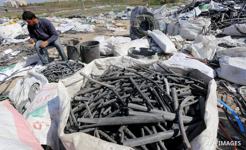 A Palestinian man collects plastics and metals from a pile of waste in Gaza city, February 22, 2017. Workers collect the household recyclables, metals and plastic from landfill and garbage to sell to the local factories....