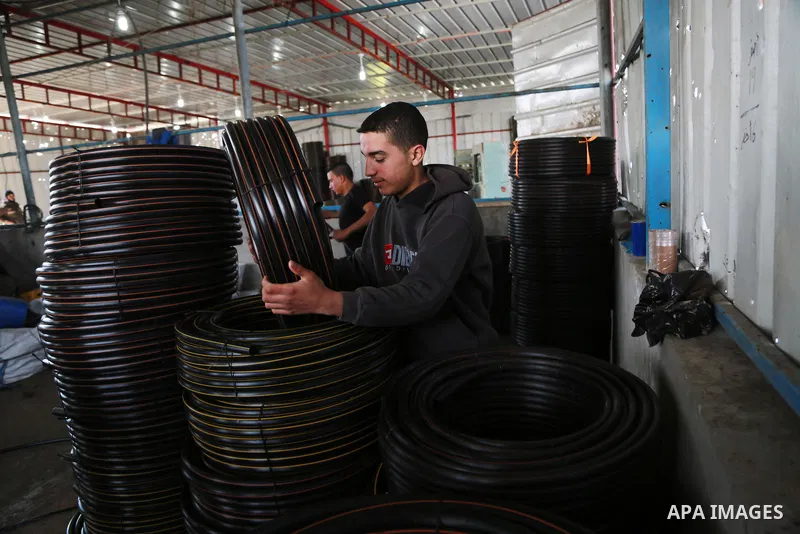 A Palestinian worker reuses plastics and metals to produce water hoses at a factory, in Gaza city, February 22, 2017. Workers collect the household recyclables, metals and plastic from landfill and garbage to sell to the...