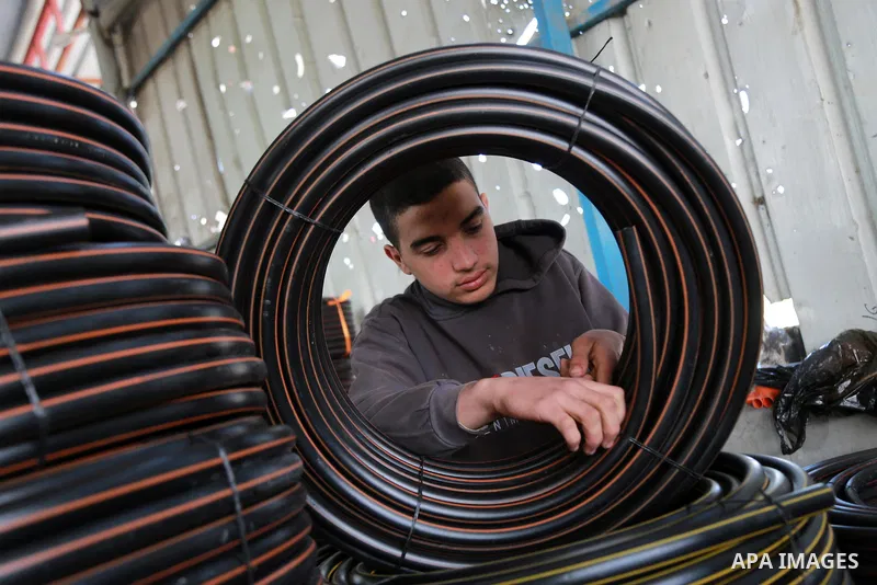 A Palestinian worker reuses plastics and metals to produce water hoses at a factory, in Gaza city, February 22, 2017. Workers collect the household recyclables, metals and plastic from landfill and garbage to sell to the...