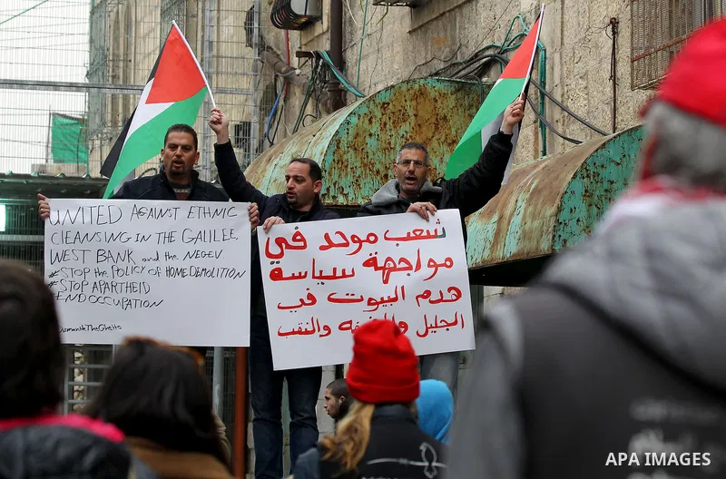 Palestinian protesters hold placards during a demonstration against the closure of Shuhada street, on the 23rd anniversary of the closure, on February 22, 2017 in the West Bank city of Hebron. On February 25, 1994 Israel...