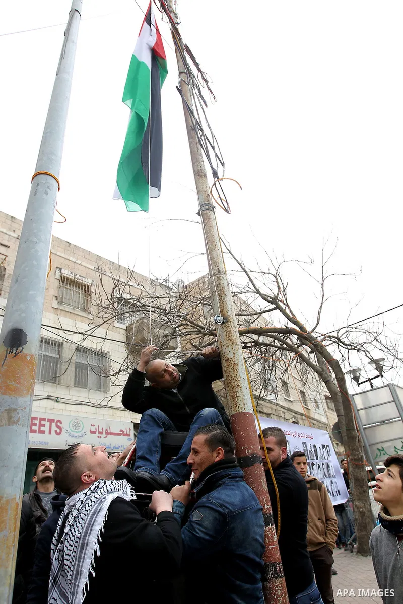 A Palestinian protester raises a palestinian flag during a demonstration against the closure of Shuhada street, on the 23rd anniversary of the closure, on February 22, 2017 in the West Bank city of Hebron. On February 25...