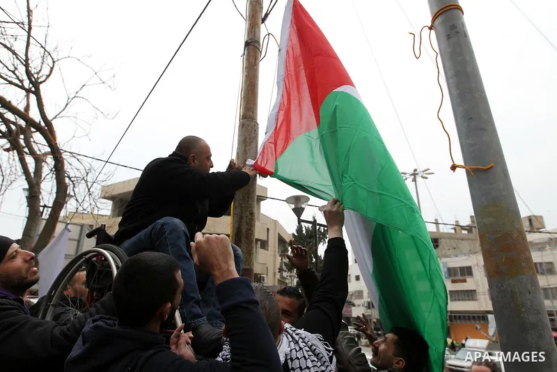 A Palestinian protester raises a palestinian flag during a demonstration against the closure of Shuhada street, on the 23rd anniversary of the closure, on February 22, 2017 in the West Bank city of Hebron. On February 25...