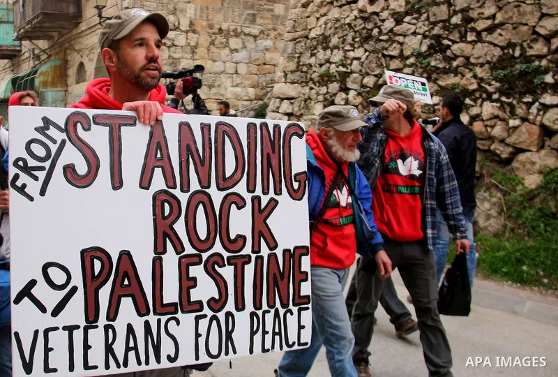 Palestinian protesters hold placards during a demonstration against the closure of Shuhada street, on the 23rd anniversary of the closure, on February 22, 2017 in the West Bank city of Hebron. On February 25, 1994 Israel...