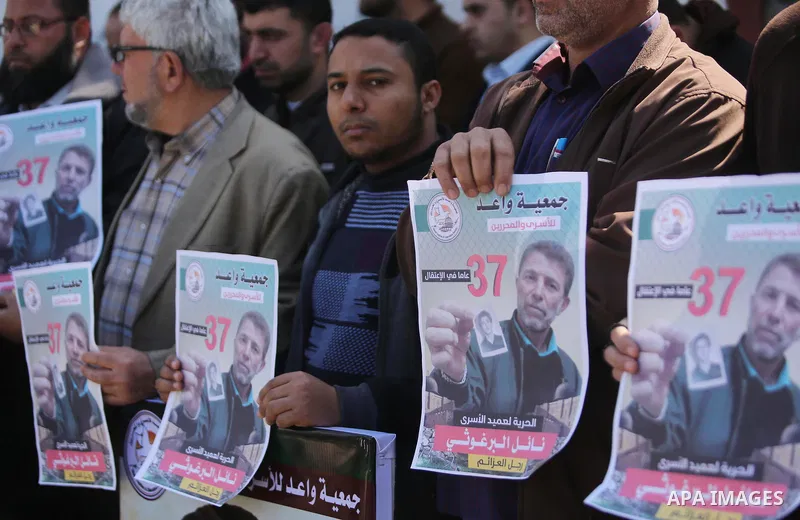 Palestinians hold placards during a protest to show solidarity with Palestinian prisoner Nael Barghouthi, held in Israeli Jails, in Gaza city, on February 23, 2017. Photo by Ashraf Amra