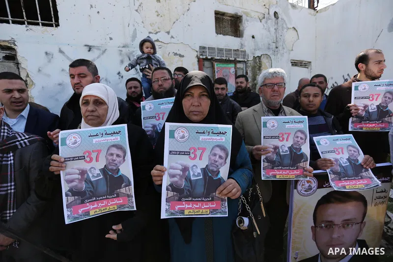 Palestinians hold placards during a protest to show solidarity with Palestinian prisoner Nael Barghouthi, held in Israeli Jails, in Gaza city, on February 23, 2017. Photo by Ashraf Amra