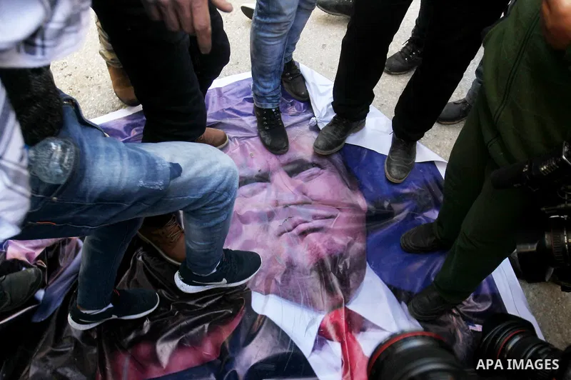 Palestinian demonstrators step on a poster of US President Donald Trump as they protest against his support of Israel and demand for the Israeli army to re-open Shuhada Street, which is largely closed off to Palestinians...