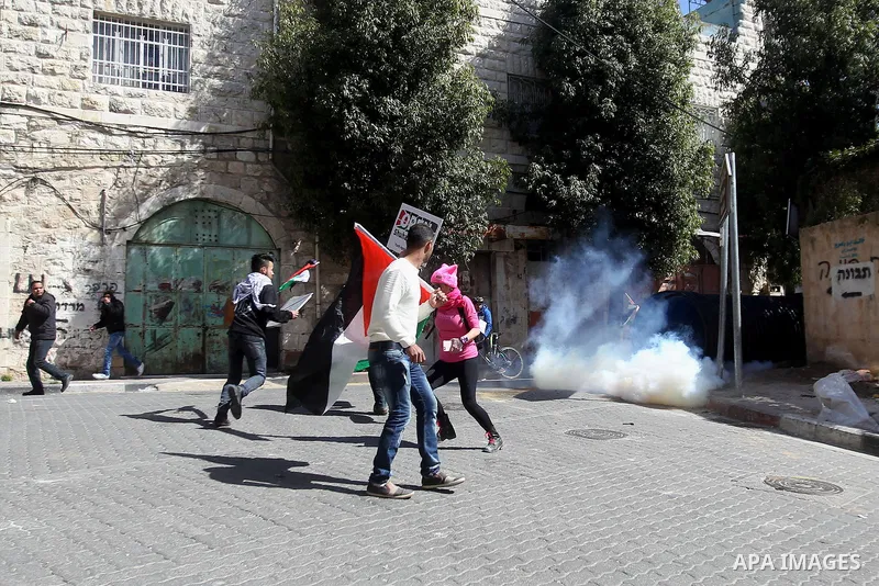 Palestinian and foreign protesters run from a tear gas canister fired by Israeli security forces during clashes calling for the opening of Shuhada Street, which is largely closed off to Palestinians, in the West Bank cit...