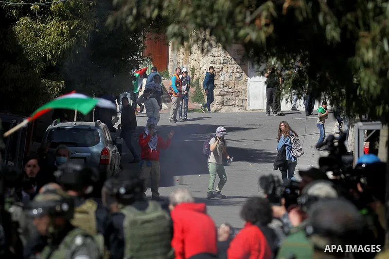 Palestinian and foreign protesters run from a tear gas canister fired by Israeli security forces during clashes calling for the opening of Shuhada Street, which is largely closed off to Palestinians, in the West Bank cit...