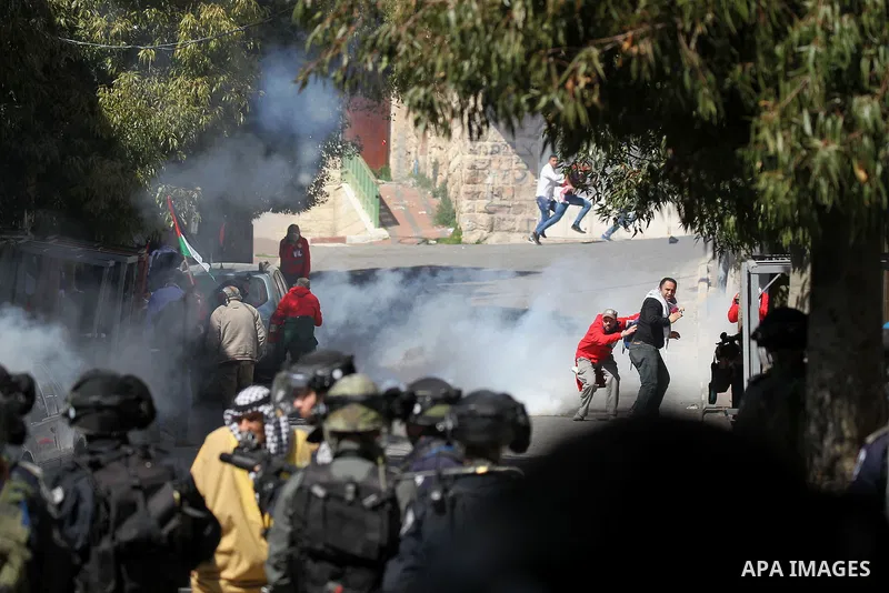 Palestinian and foreign protesters run from a tear gas canister fired by Israeli security forces during clashes calling for the opening of Shuhada Street, which is largely closed off to Palestinians, in the West Bank cit...