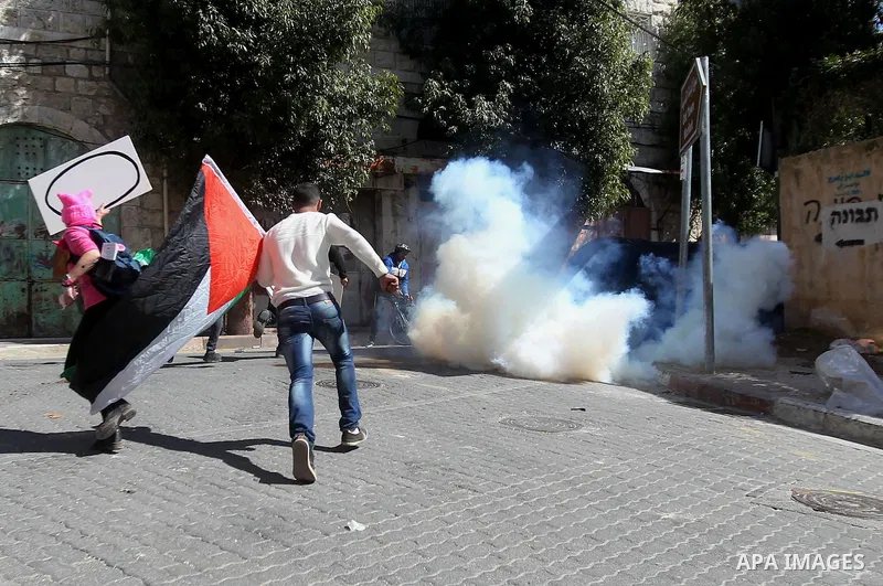 Palestinian and foreign protesters run from a tear gas canister fired by Israeli security forces during clashes calling for the opening of Shuhada Street, which is largely closed off to Palestinians, in the West Bank cit...