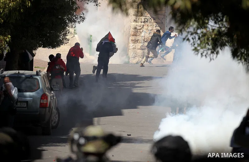 Palestinian and foreign protesters run from a tear gas canister fired by Israeli security forces during clashes calling for the opening of Shuhada Street, which is largely closed off to Palestinians, in the West Bank cit...