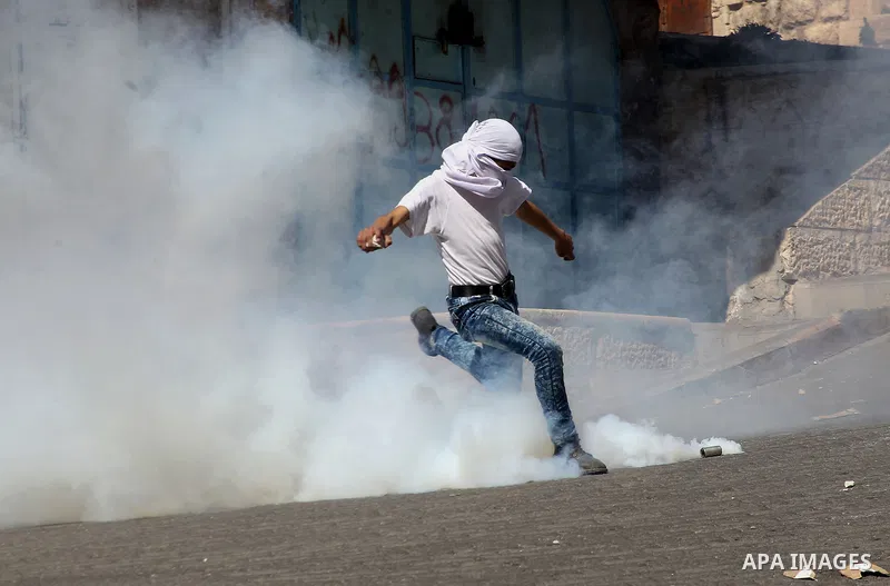 A Palestinian protester kicks a tear gas canister fired by Israeli security forces during clashes calling for the opening of Shuhada Street, which is largely closed off to Palestinians, in the West Bank city of Hebron, c...