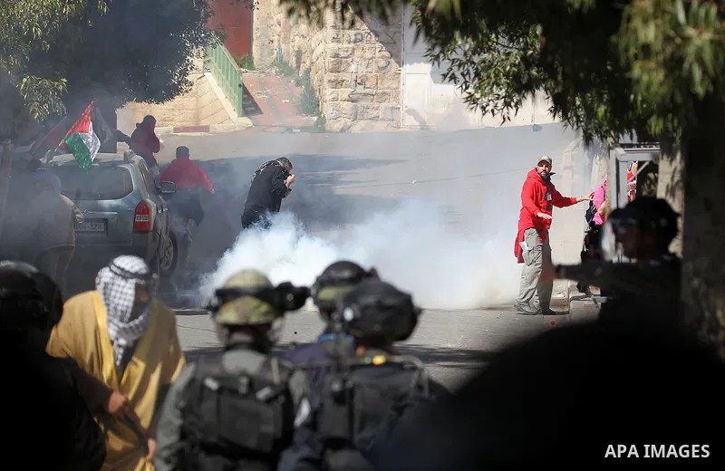 Palestinian and foreign protesters run from a tear gas canister fired by Israeli security forces during clashes calling for the opening of Shuhada Street, which is largely closed off to Palestinians, in the West Bank cit...