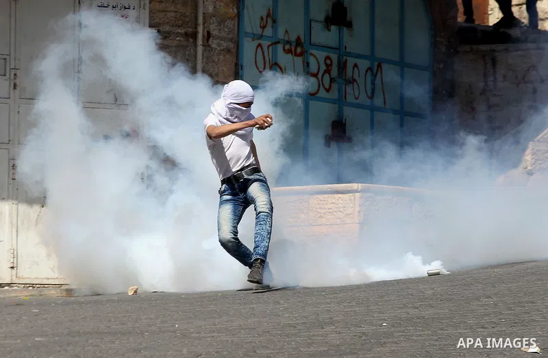 A Palestinian protester kicks a tear gas canister fired by Israeli security forces during clashes calling for the opening of Shuhada Street, which is largely closed off to Palestinians, in the West Bank city of Hebron, c...