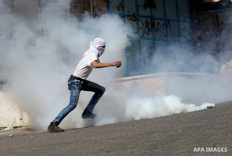 A Palestinian protester kicks a tear gas canister fired by Israeli security forces during clashes calling for the opening of Shuhada Street, which is largely closed off to Palestinians, in the West Bank city of Hebron, c...