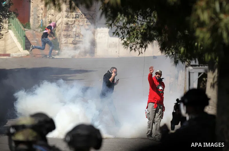 Palestinian and foreign protesters run from a tear gas canister fired by Israeli security forces during clashes calling for the opening of Shuhada Street, which is largely closed off to Palestinians, in the West Bank cit...