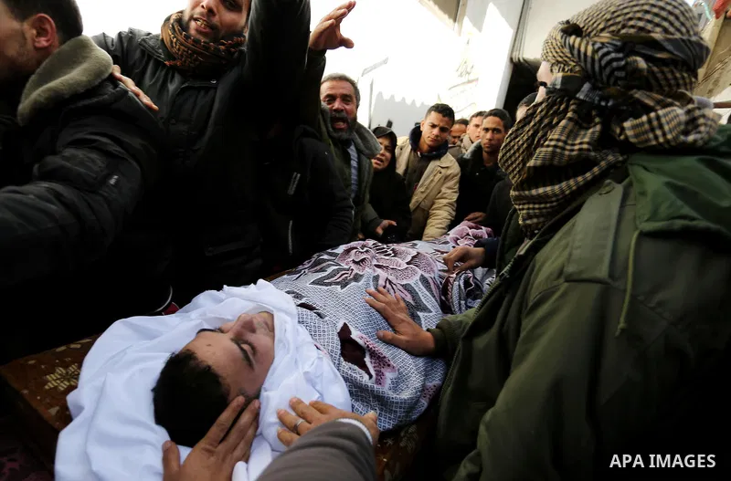 Palestinians mourn around the body of Palestinian Abdullah Alnamula, 23, who died after inhaling toxic gas inside the tunnel along the border between the Gaza Strip and Egypt during his funeral in Rafah in the southern G...
