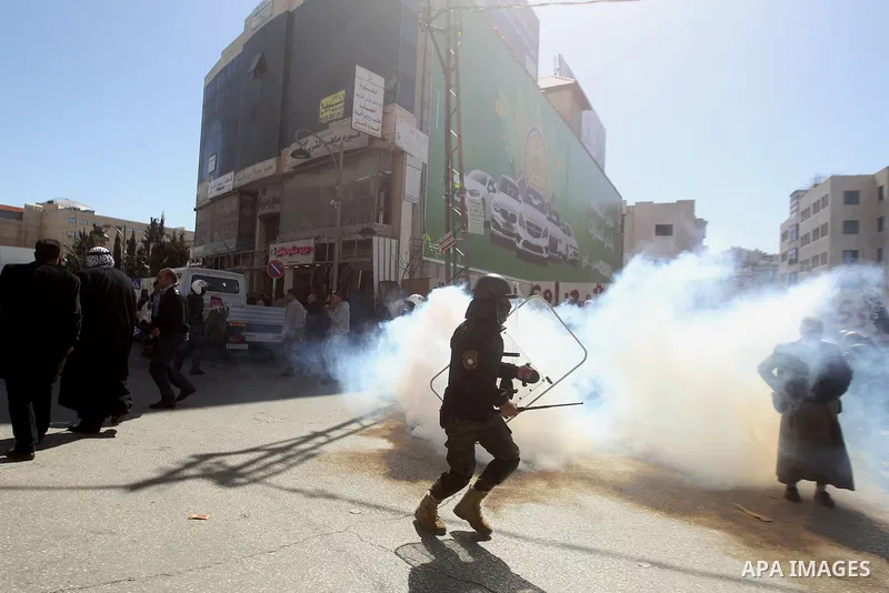 A Palestinian security officer reacts to tear gas during clashes at a protest organised by Hizb-ut Tahrir against what organisers say are political arrests by the Palestinian Authority in the West Bank city of Hebron Feb...