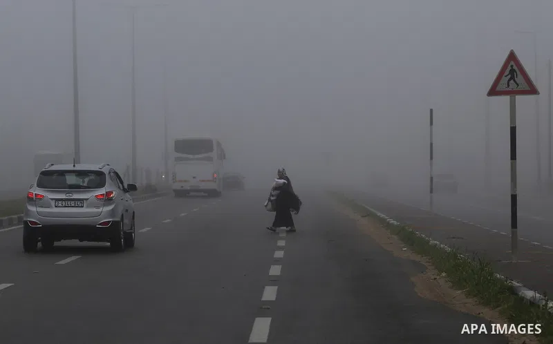 Palestinians walk at a street during foggy morning in Gaza city, on February 26, 2017. Photo by Yasser Qudih