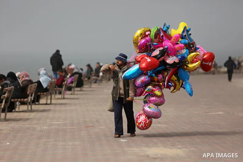 A Palestinian vendor sells balloons at the Gaza seaport, during foggy morning, on February 26, 2017. Photo by Ashraf Amra