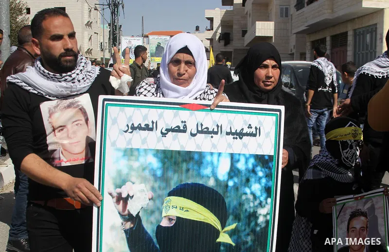 Masked Palestinians holds the pictures of Palestinian teenager Qusai Al-Amour, a 17-year-old who was shot dead, during a demonstration in the West Bank village of Tuqua, near Bethlehem, 26 February 2017. Emoor, a member...